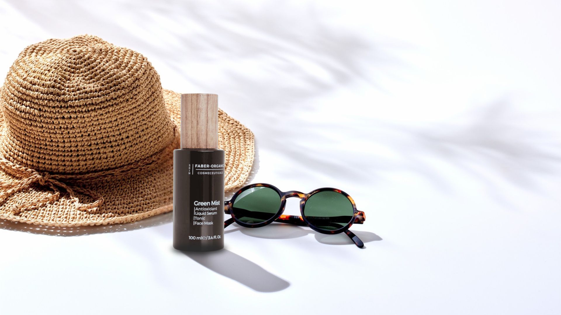 Flacone Green Mist a tema estivo con cappello di paglia e occhiali da sole, simbolo di skincare minimalista estiva e rigenerazione profonda secondo Faber-Organic